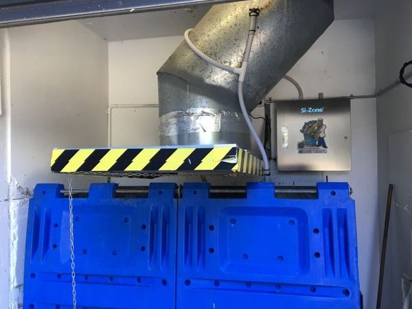 A garbage chute's hopper over blue bins, with a Garbage Doctor unit and its hose into the bin beside it