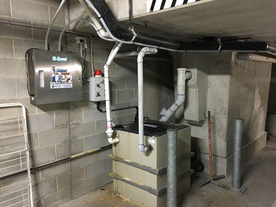 An Odour Doctor unit on the wall with its ozone pipework running down to a grease trap